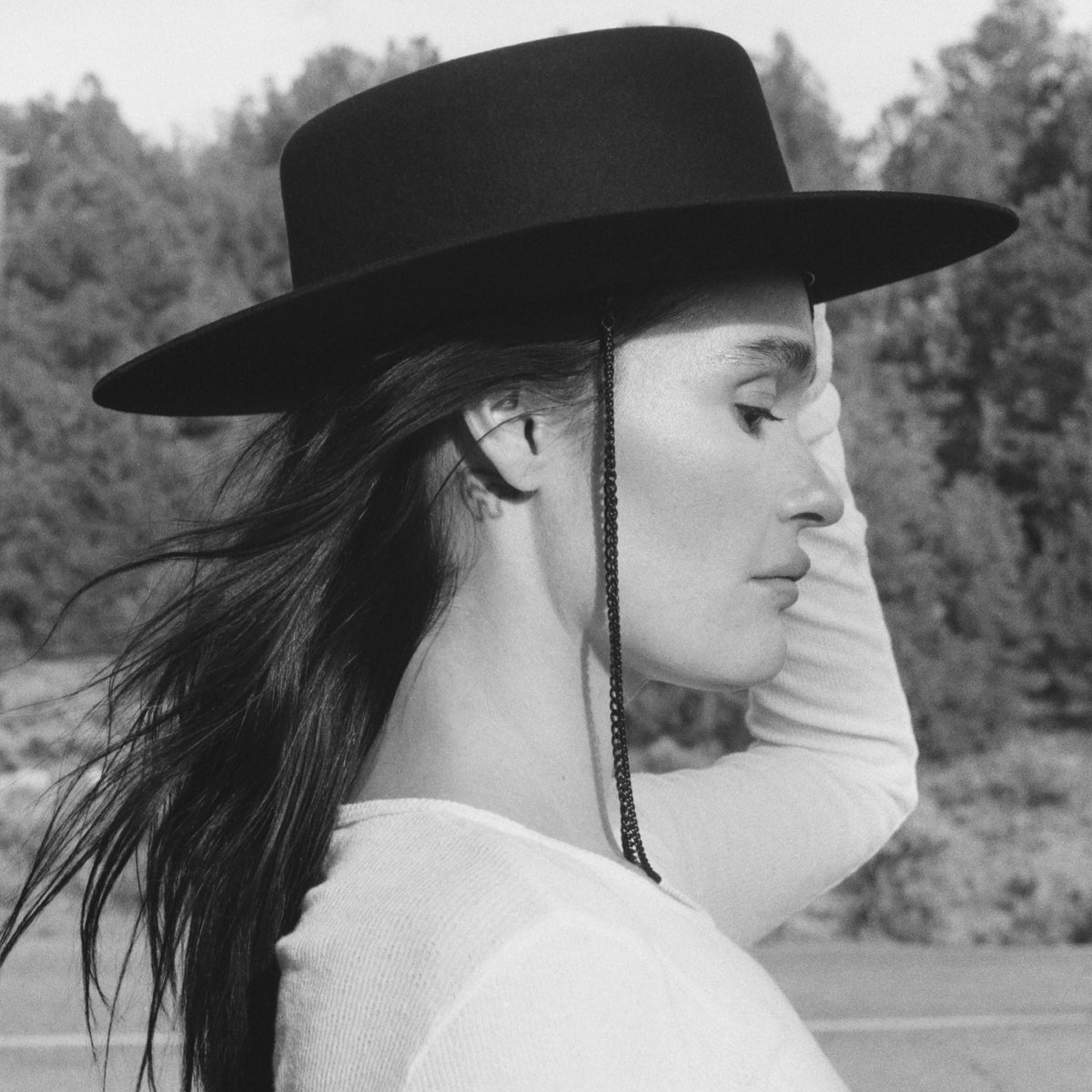Editorial black and white profile photograph of a model wearing The Noir black beaver hat by Storm with draped chain detail.