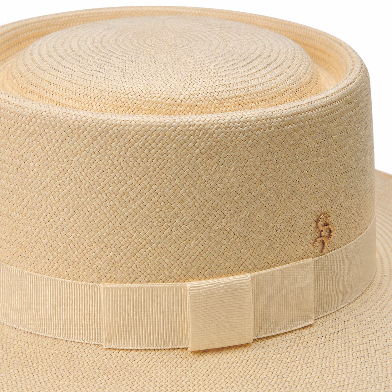 Detailed macro view of the hand-woven Colombian Toquilla straw on The 505 hat, highlighting the signature gold-plated Storm logo pin and structured cream block bow.