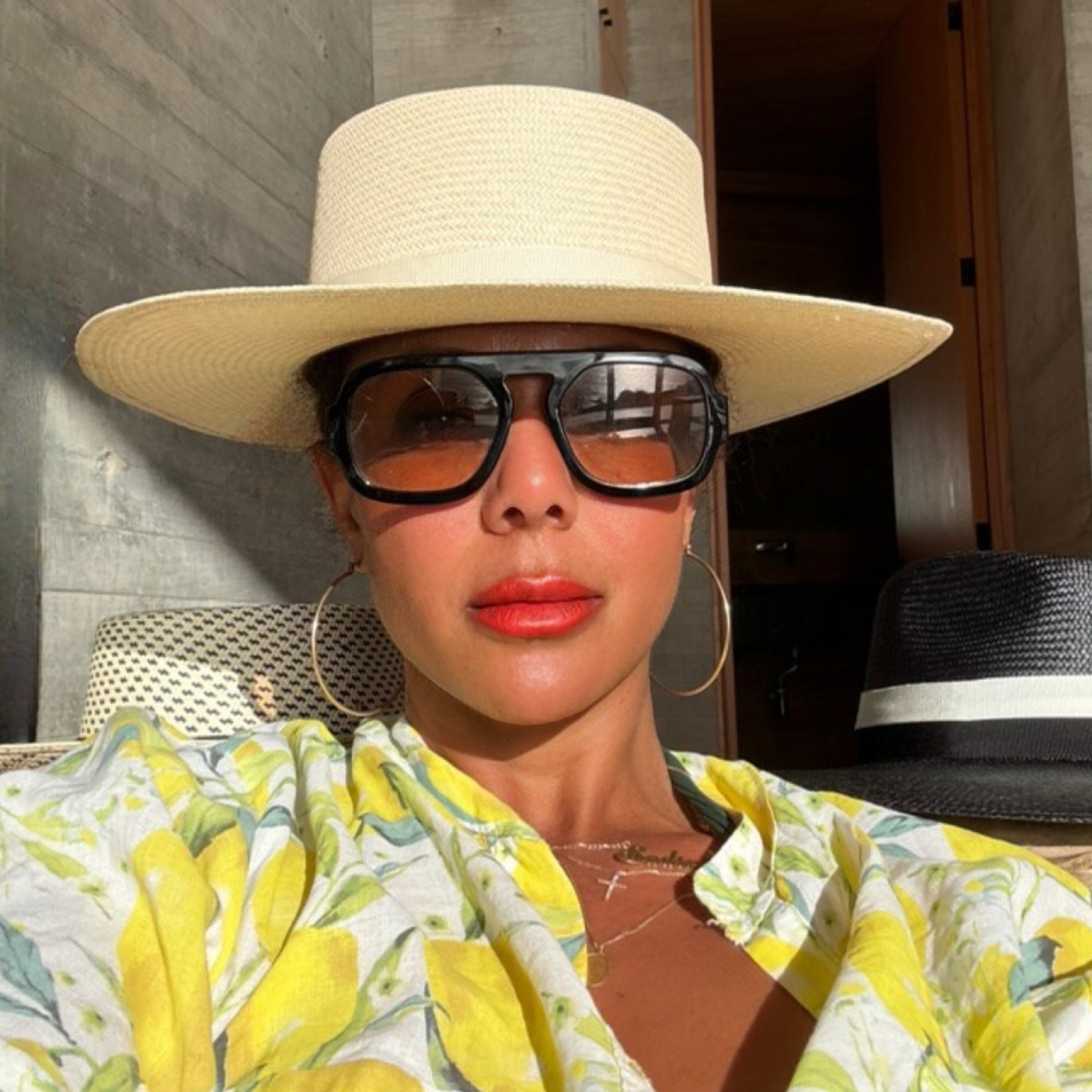 Resort styling of The 505 telescope straw hat by Storm, worn by a model in a lemon-print linen shirt and bold black sunglasses.